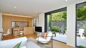 A modern living room with a sofa, a TV, and a dining area with chairs.