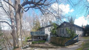 A two-story house with a balcony, a stone foundation, and a staircase leading to the entrance.