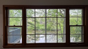 A room with a large window overlooking a pond and trees.