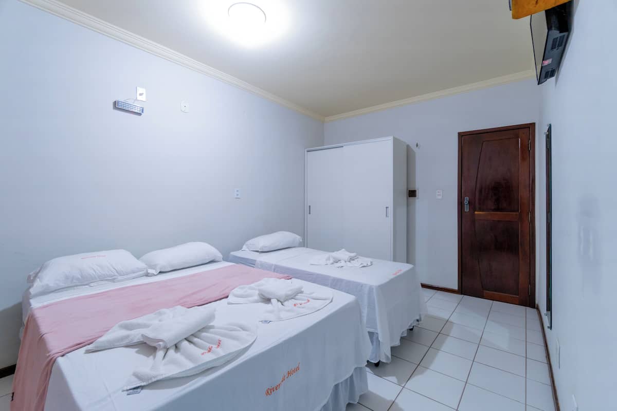 Une chambre d’hôtel avec deux lits simples, un réfrigérateur blanc, une porte en bois et un sol carrelé de couleur blanche.
