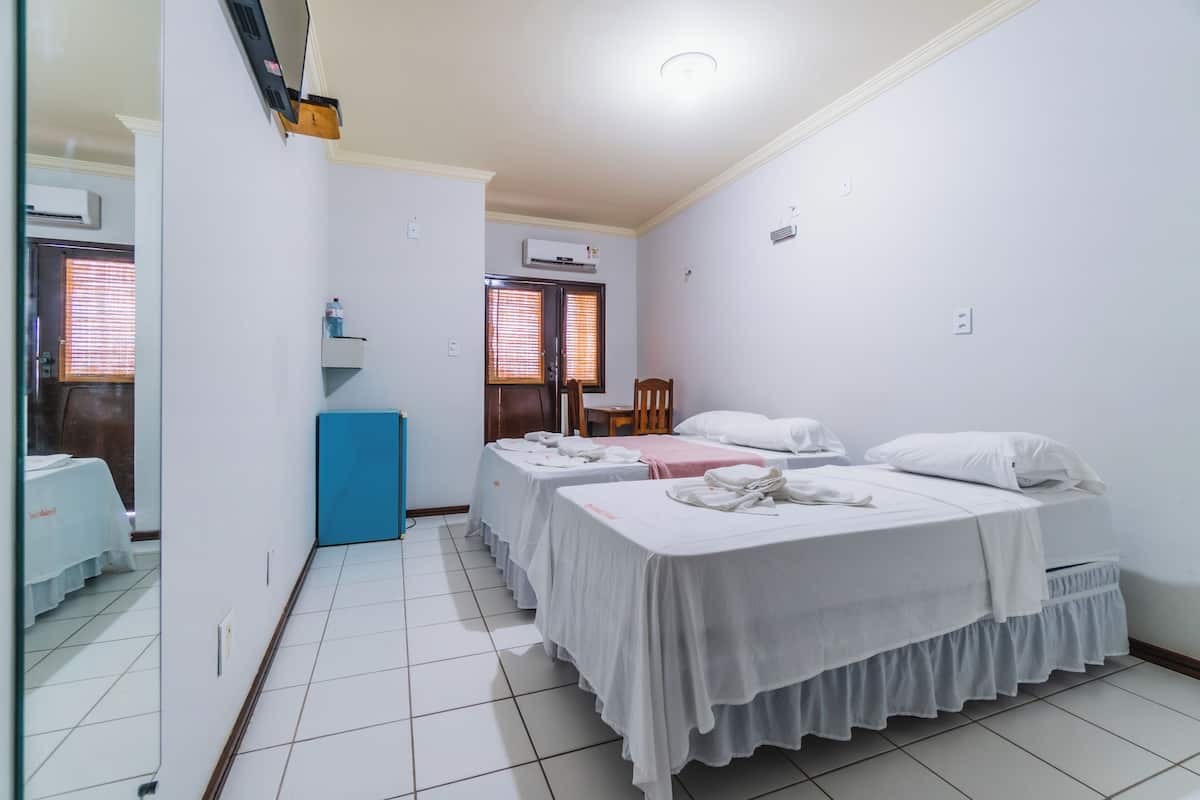 Une chambre d’hôtel avec deux lits, une armoire bleue et un miroir.