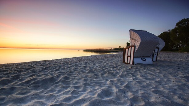Una playa con una estructura de silla moderna y singular, marcada con los números '50' y '6'.