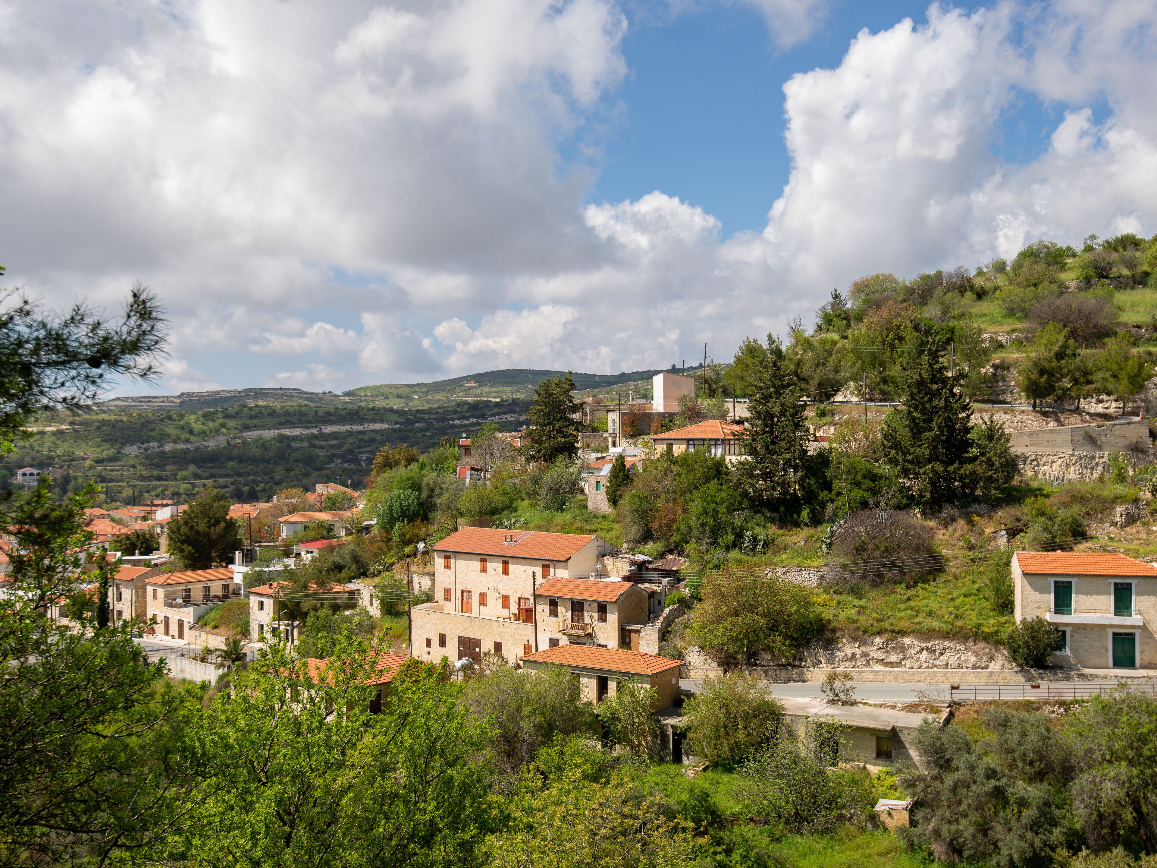 A hillside village with traditional stone buildings, terraced houses, and a river.