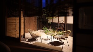 A patio with two wicker chairs and a small table, surrounded by plants and a wooden fence. - Nipponia Izumo Taisha Shrine Town (Izumo)