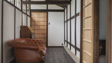 A traditional Japanese room with tatami flooring, a brown leather sofa, and wooden sliding doors.