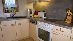 A kitchen with a dishwasher, oven, microwave, and a fruit bowl on the counter. - The Perfect House to Stay for Holidays (Oberharz am Brocken)
