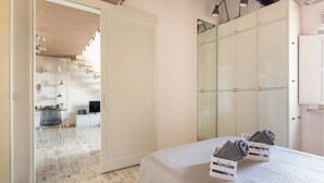 Ein Schlafzimmer mit Bett, Kleiderschrank und einem durchgegangenen Tür sichtbaren Badezimmer.