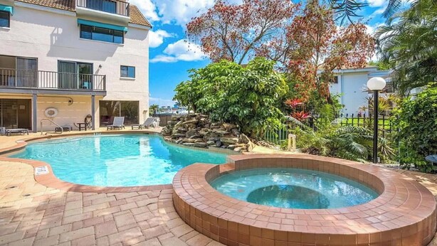 A swimming pool with a hot tub, surrounded by a brick patio and lush greenery. - Beautiful waterfront view property. Only 5 minutes from the beaches! (Clearwater)