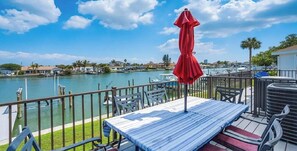 A deck with a table and chairs, overlooking a marina with boats and a body of water.