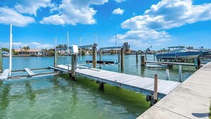 A marina with wooden docks extending into calm water, surrounded by residential buildings and a clear sky. - Beautiful waterfront view property. Only 5 minutes from the beaches! (Clearwater)
