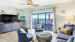 A living room with a sofa, armchairs, a coffee table, and a TV. There is a balcony with a view of the marina. - Beautiful waterfront view property. Only 5 minutes from the beaches! (Clearwater)