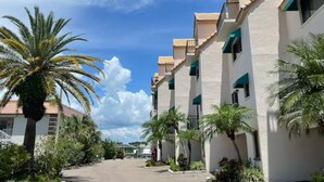 A row of white buildings with green awnings, palm trees, and a clear sky. - Beautiful waterfront view property. Only 5 minutes from the beaches! (Clearwater)