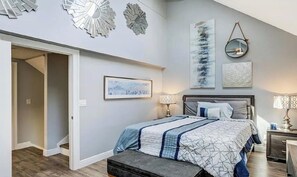 Une chambre à coucher comprenant un lit, des tables de chevet, un banc et des œuvres d’art murales.