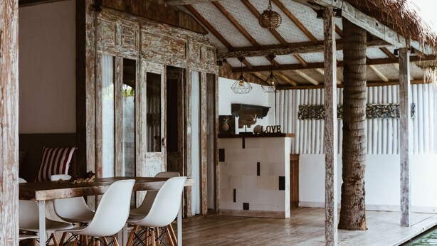 A rustic dining area with a wooden table and white chairs, a bar area with a 'LOVE' sign, and a poolside view. - CAMILLA RESORT (Gili Air)