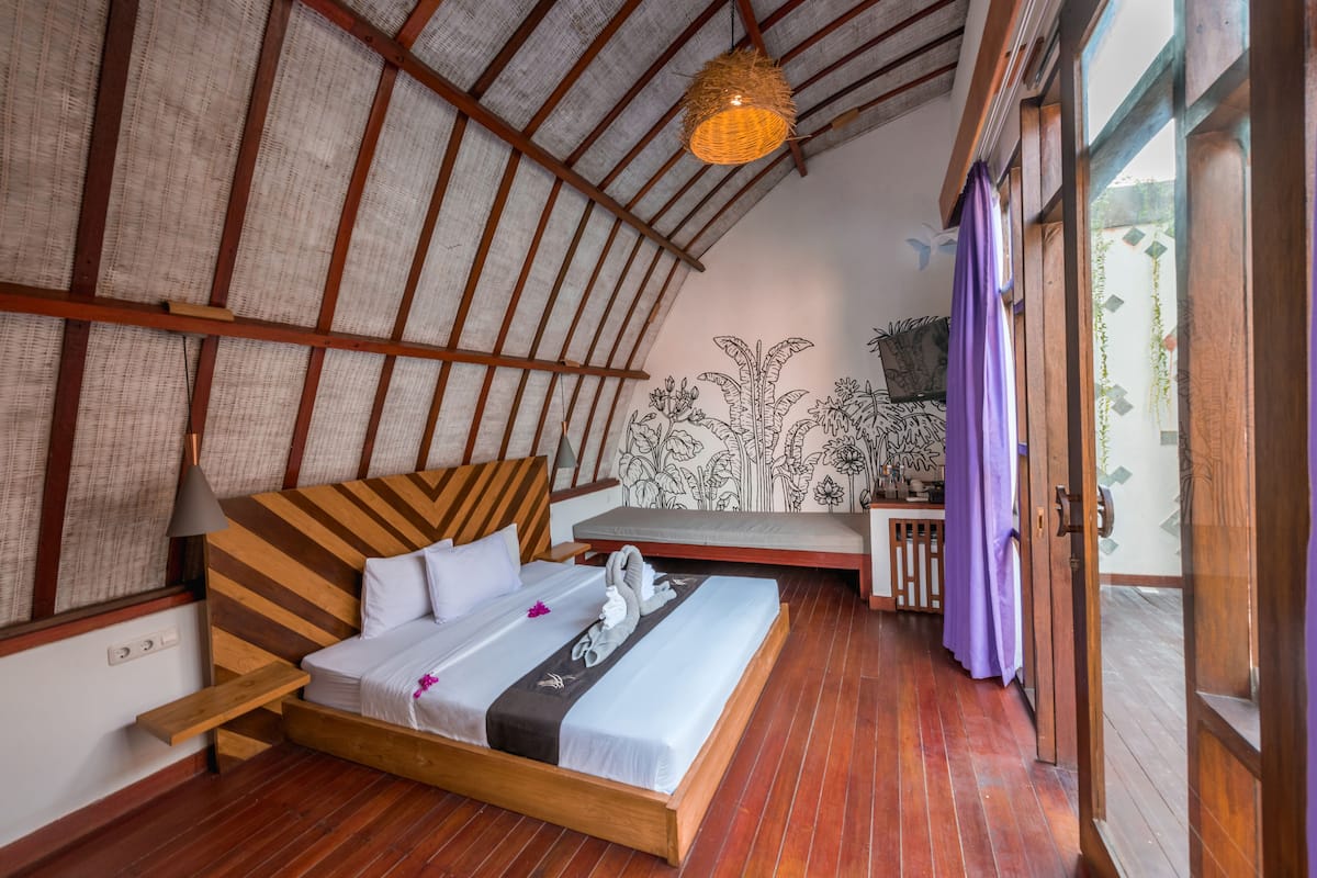 A room with a wooden bed, a bench, and a hanging light fixture.