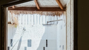 A room with a stone statue, a thatched roof, and a patterned wall. - CAMILLA RESORT (Gili Air)