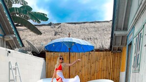 A swimming pool with lounge chairs and a bamboo fence in the background. - CAMILLA RESORT (Gili Air)