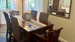 A dining area with a wooden table, wicker chairs, and a patterned rug.