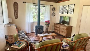 A cozy living room with a sofa, chairs, a table, a TV, a wooden cabinet, and a fireplace.