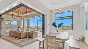 A spacious living area with a large window, a dining table, and a seating arrangement.