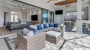A spacious living area with a large sectional sofa, a wicker coffee table, and a ceiling fan.