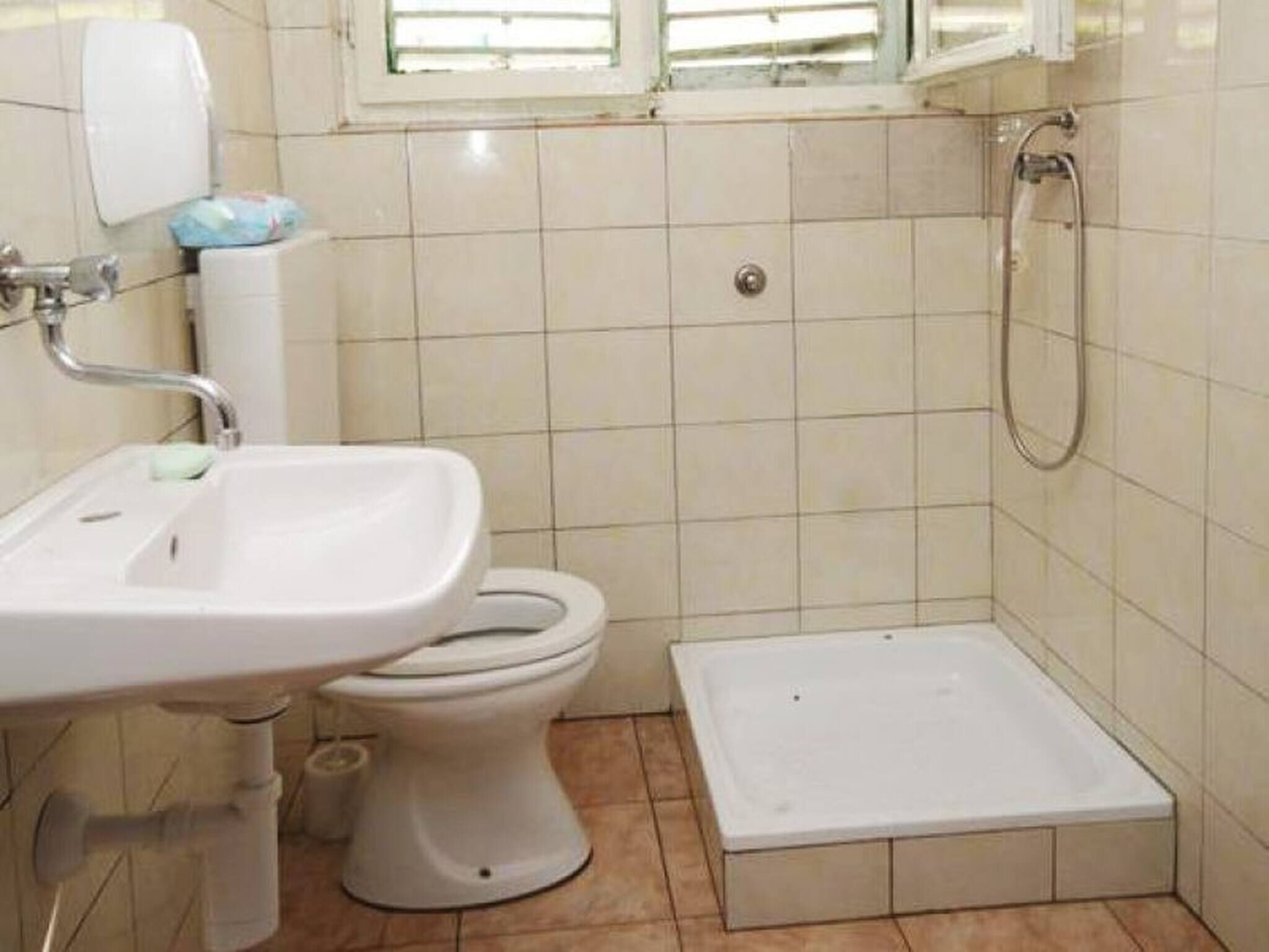 Un baño pequeño con inodoro, lavamanos y ducha.