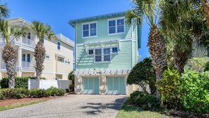 A two-story building with a light green exterior, a covered front porch, and a paved driveway. - Large Family Home, 1 minute Walk to Beach, Private Yard, Heated Pool, Elevator, $300 in Free Tickets (St. Augustine)