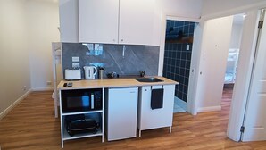 Cocina pequeña equipada con microondas, tostadora y lavaplatos.