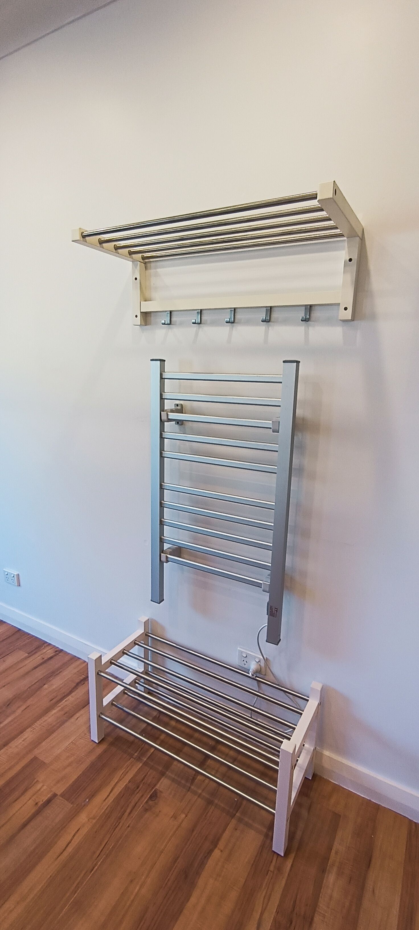 A wall-mounted drying rack with multiple levels for hanging clothes.