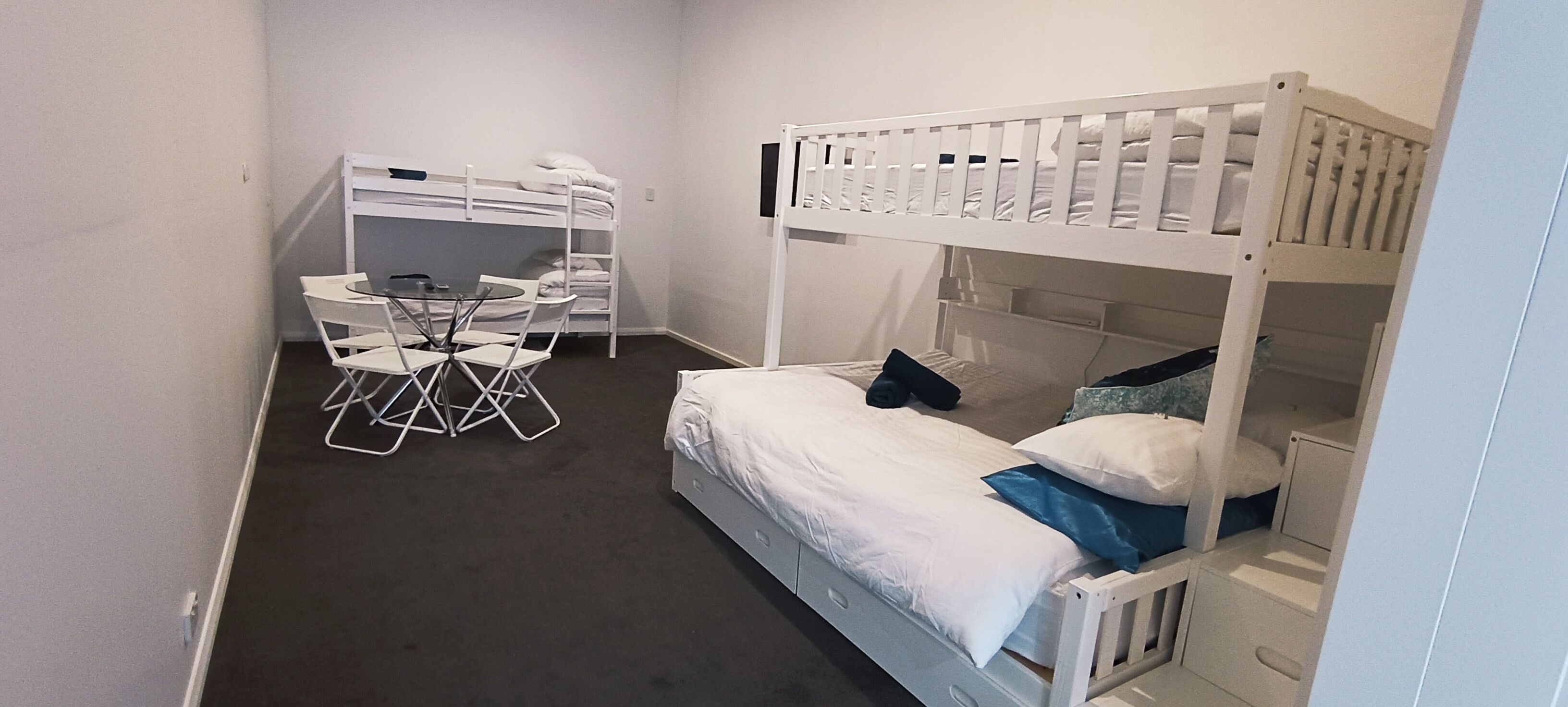 A room with a bunk bed, a desk with chairs, and a small table.