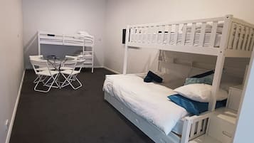 A room with a bunk bed, a desk with chairs, and a small table.