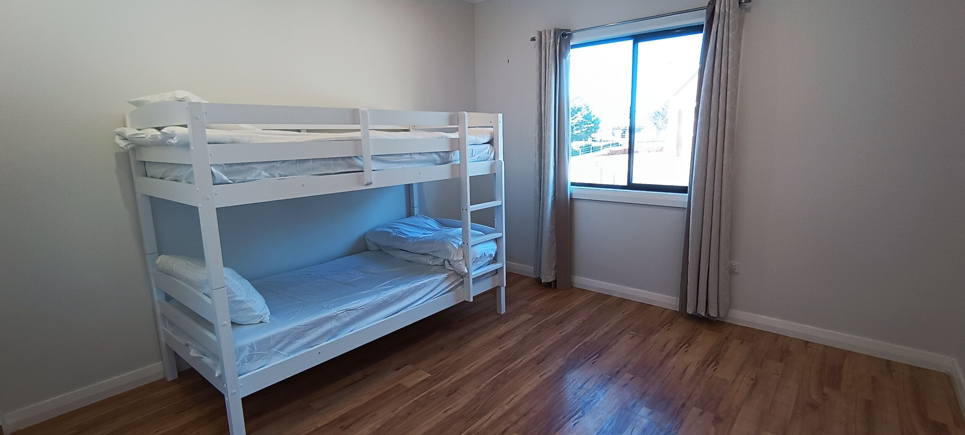 Dormitorio con literas, ventana y cortinas.