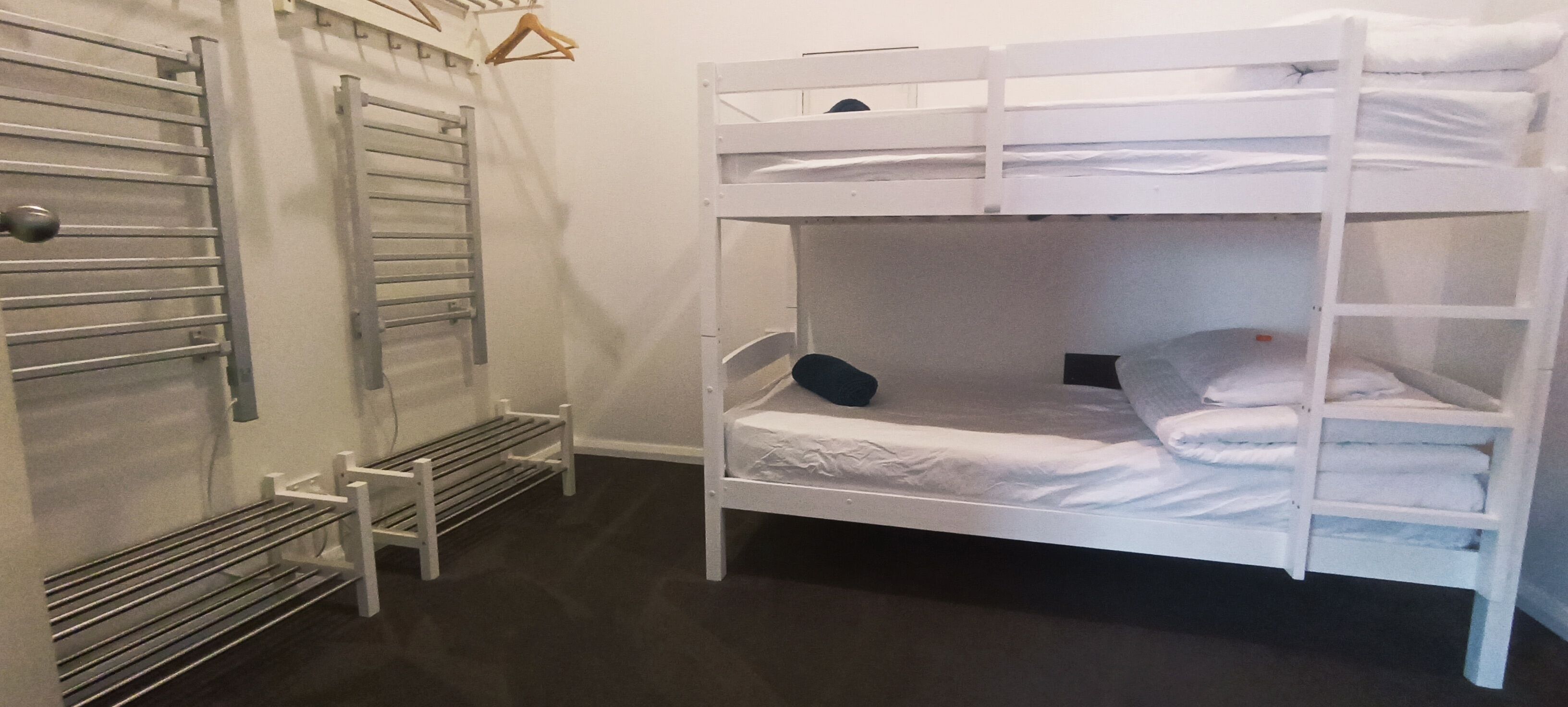 A bunk bed room with a metal rack and a bench.