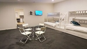 Una habitación con literas, televisión y una mesa de comedor con sillas.