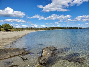 A clear beach with visible rocks and a forested shoreline. - Sugar Maple Farm near Acadia, Bar Harbor with FirePit, Large Deck (Lamoine)
