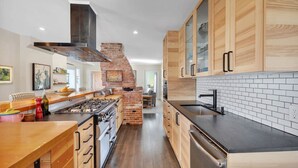 Une cuisine moderne avec des meubles en bois, une cheminée en briques et un plan de travail noir.