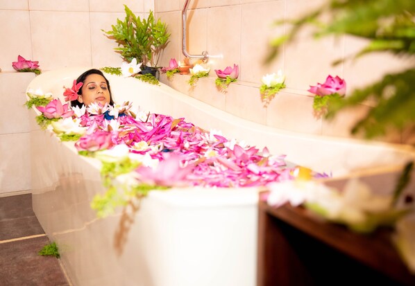 A bathtub filled with pink and white flowers, surrounded by potted plants and candles. - Ayurveda Spring of life Resort (Piliyandala)