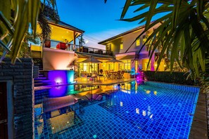 A modern house with a swimming pool, outdoor seating, and a well-lit balcony. - 3 Bed Pool Villa in Great Location - STV (Hua Hin)