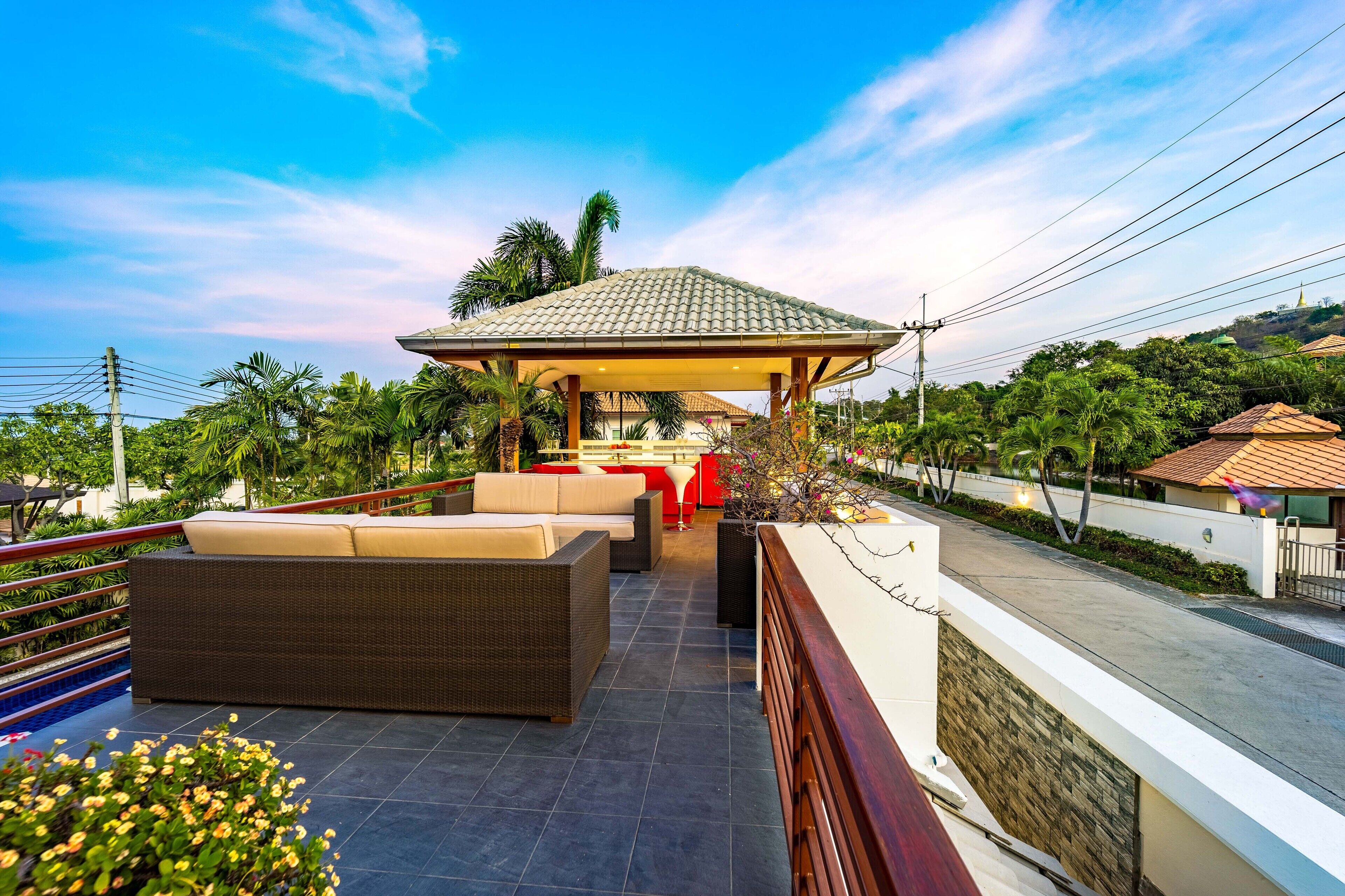 Terraço no telhado com área de estar ao ar livre, espaço coberto e vista para o verde e edifícios ao redor.