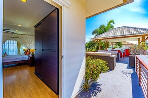A hotel room with a bed, a wardrobe, and a balcony with outdoor seating and plants. - 3 Bed Pool Villa in Great Location - STV (Hua Hin)