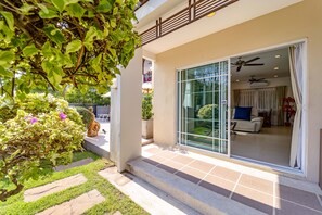 A modern house with a patio, a glass door leading to a living room, and a ceiling fan. - 3 Bed Pool Villa in Great Location - STV (Hua Hin)