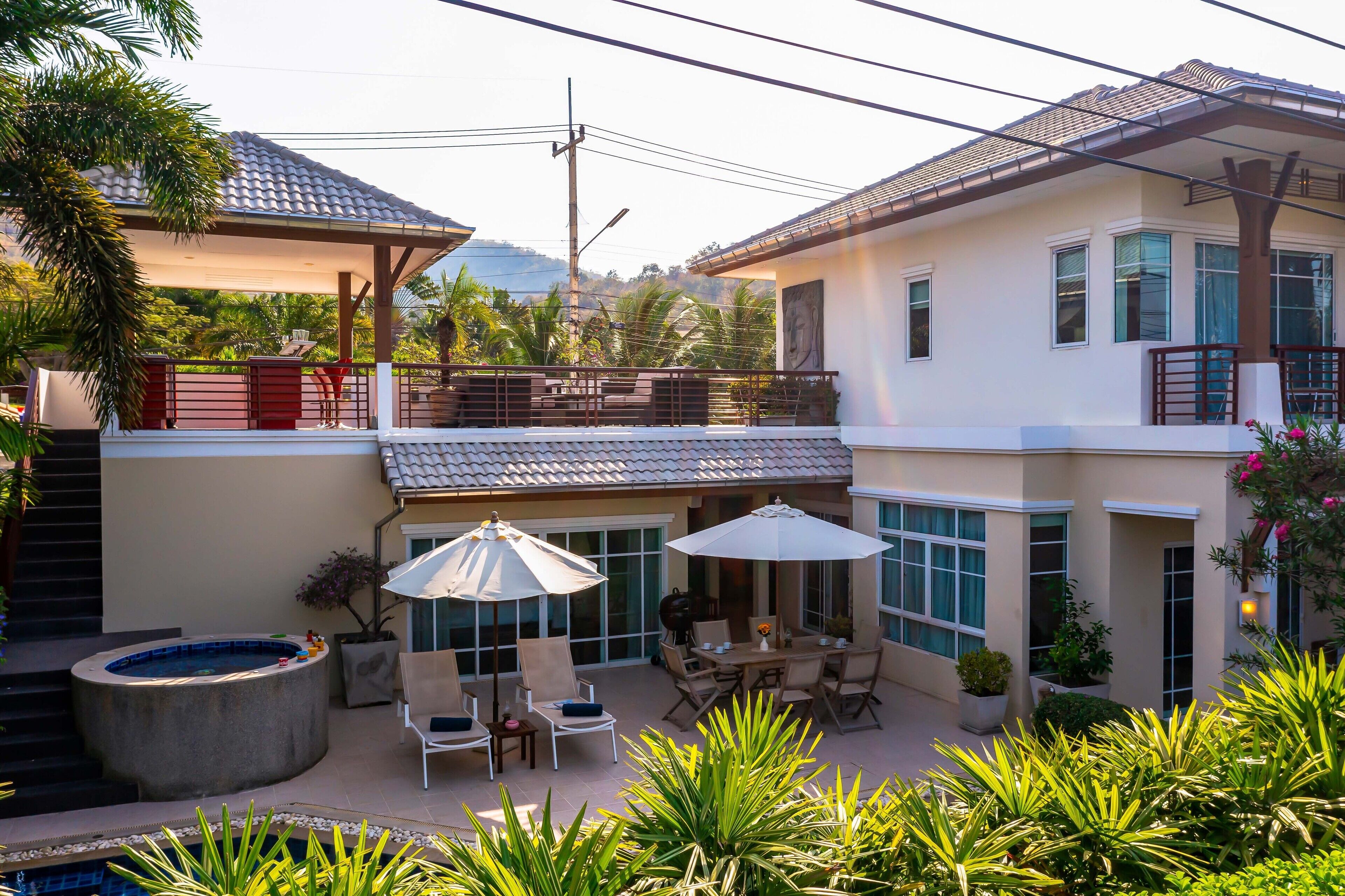 Uma casa de dois andares com um pátio, área de estar externa, hidromassagem e piscina.
