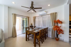 A dining area with a wooden table set for six, surrounded by chairs, a ceiling fan, and a potted plant. - 3 Bed Pool Villa in Great Location - STV (Hua Hin)