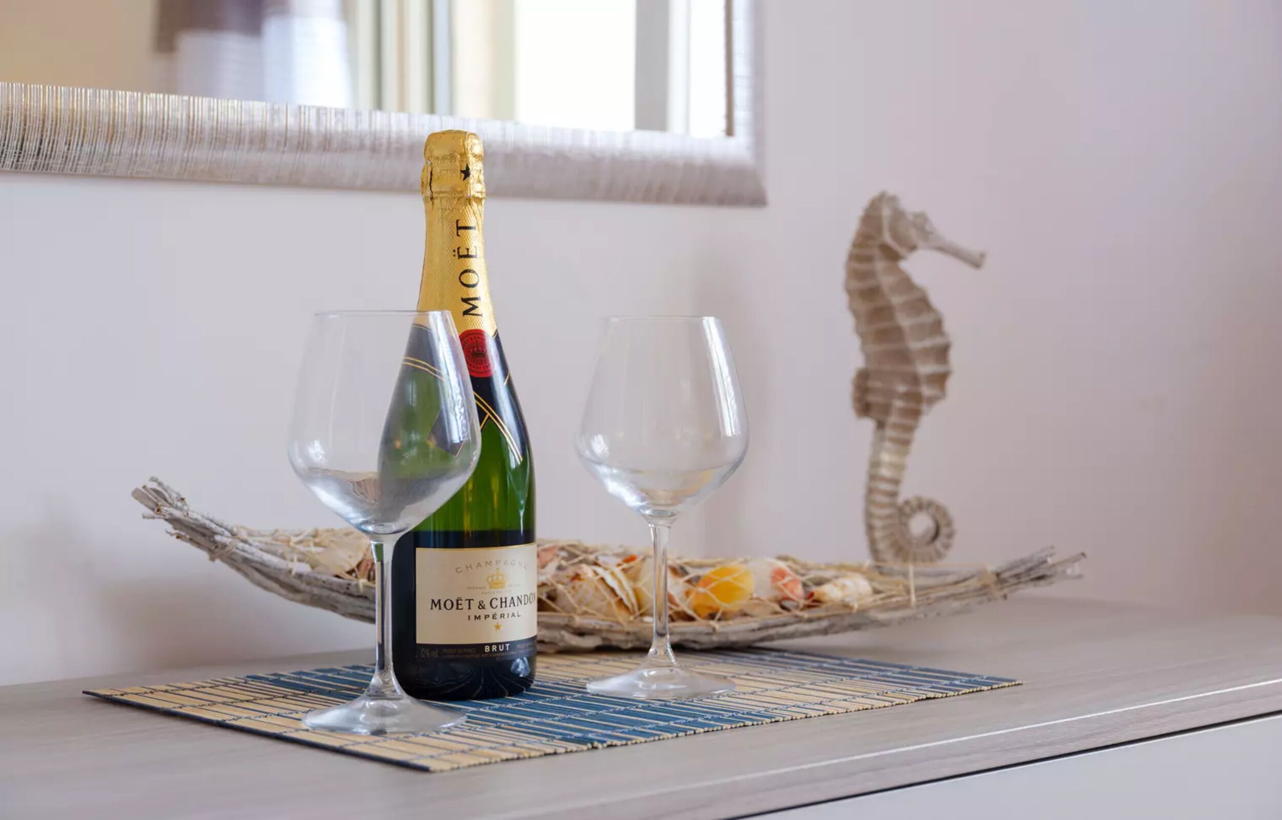 A bottle of Moët & Chandon champagne on a table with two glasses and a decorative seahorse.