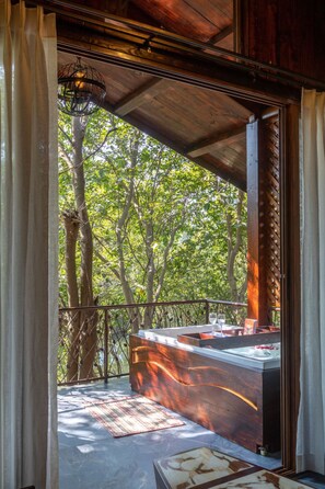 A wooden deck with a hot tub, surrounded by trees and a view of the forest. - Jalsrushti Island Resort (Paud)