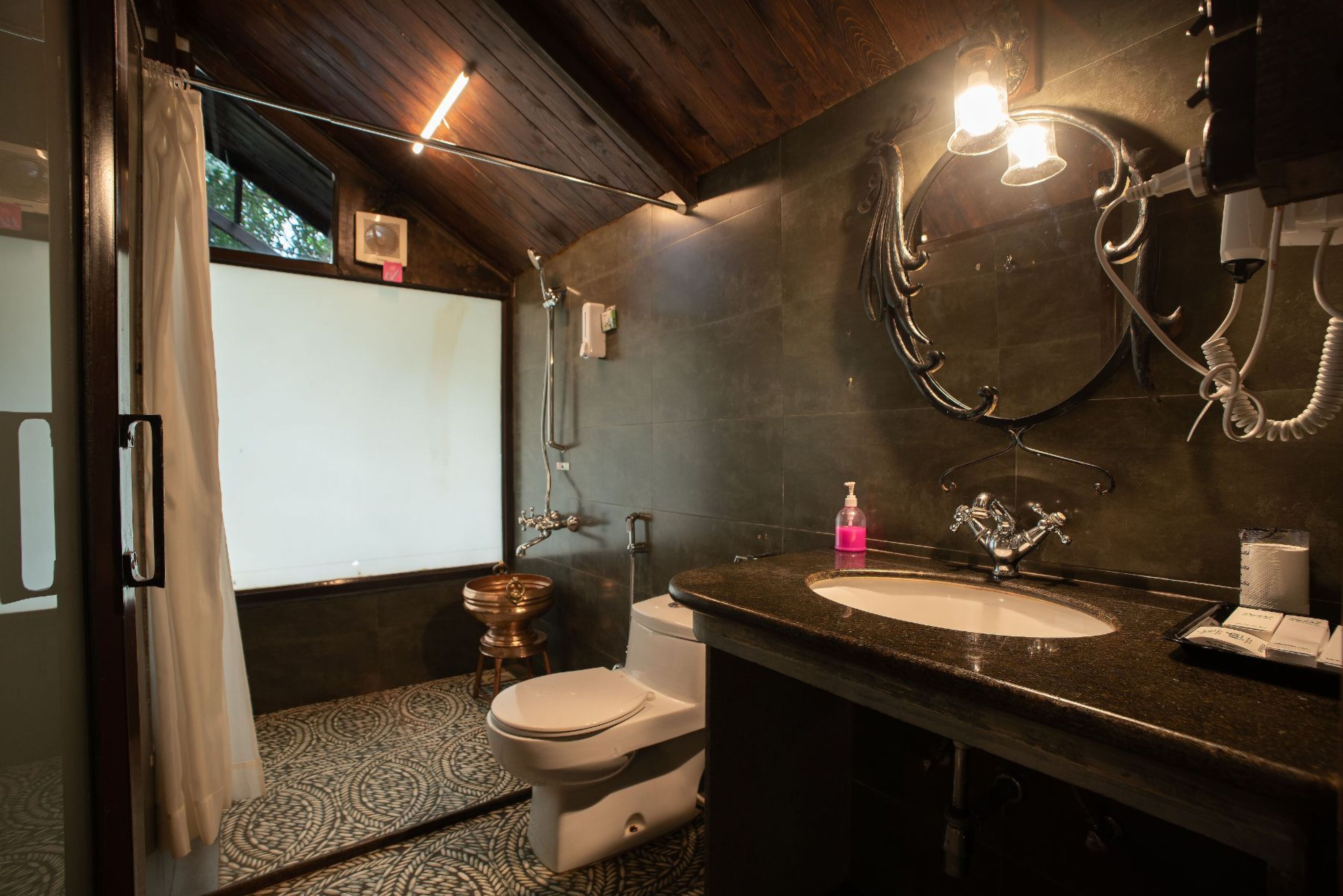 A bathroom with a wooden ceiling, a large mirror, a sink, and a toilet.
