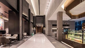 A modern hotel lobby with a central corridor, seating area, and a dessert display. - UrCove by Hyatt Shanghai Lujiazui EXPO (Shanghai)