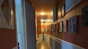 A hallway with a wooden floor, white wainscoting, and framed pictures on the walls. - Champs Élysées (Paris)