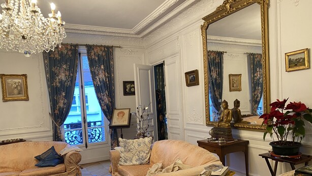 A well-furnished living room with a chandelier, two sofas, a coffee table, and a large mirror. - Champs Élysées (Paris)