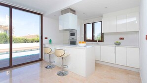 Una cucina moderna con una grande isola, sgabelli da bar e vista su una piscina.